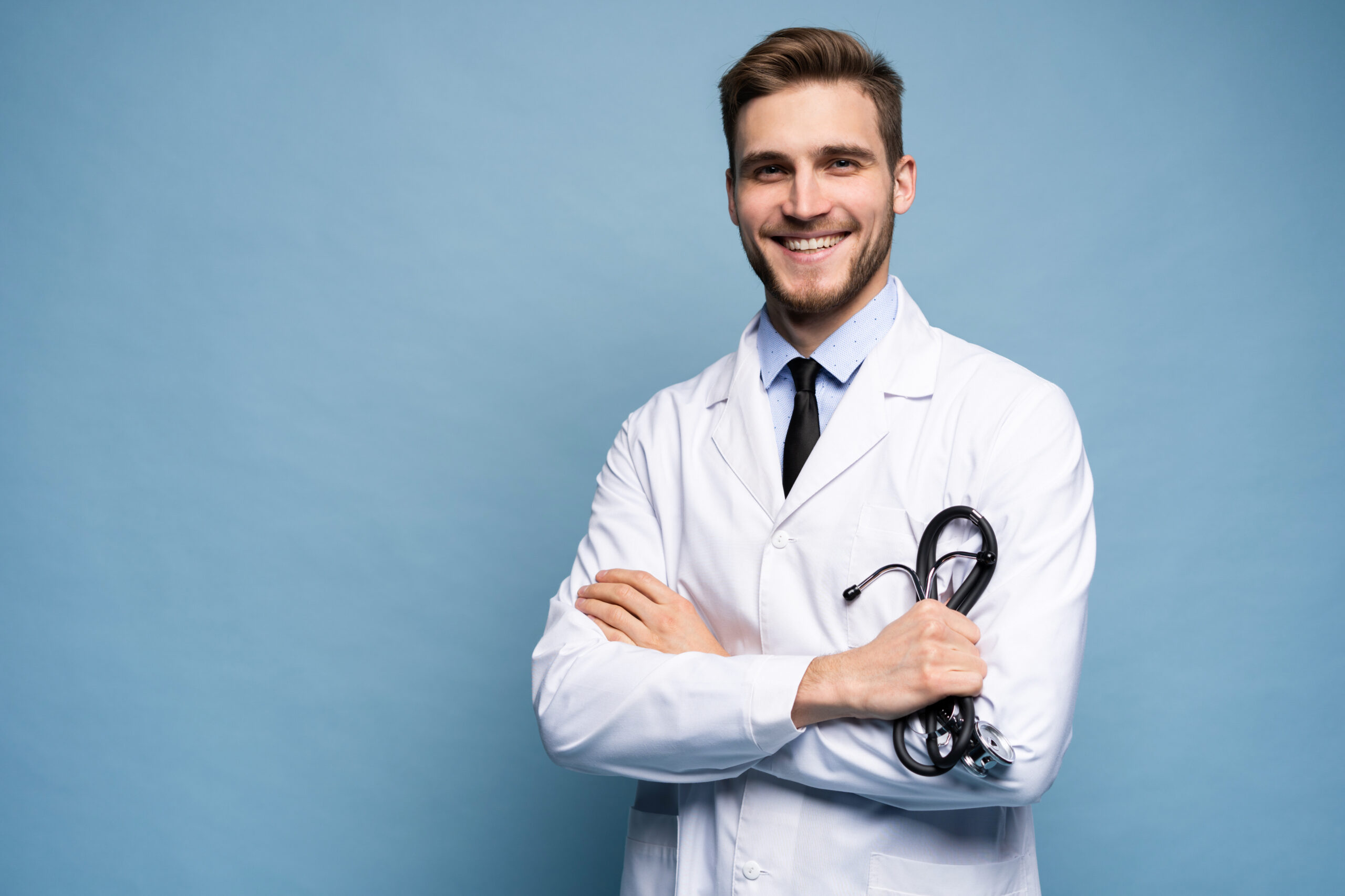 Portrait of confident young male medical doctor on blue background.