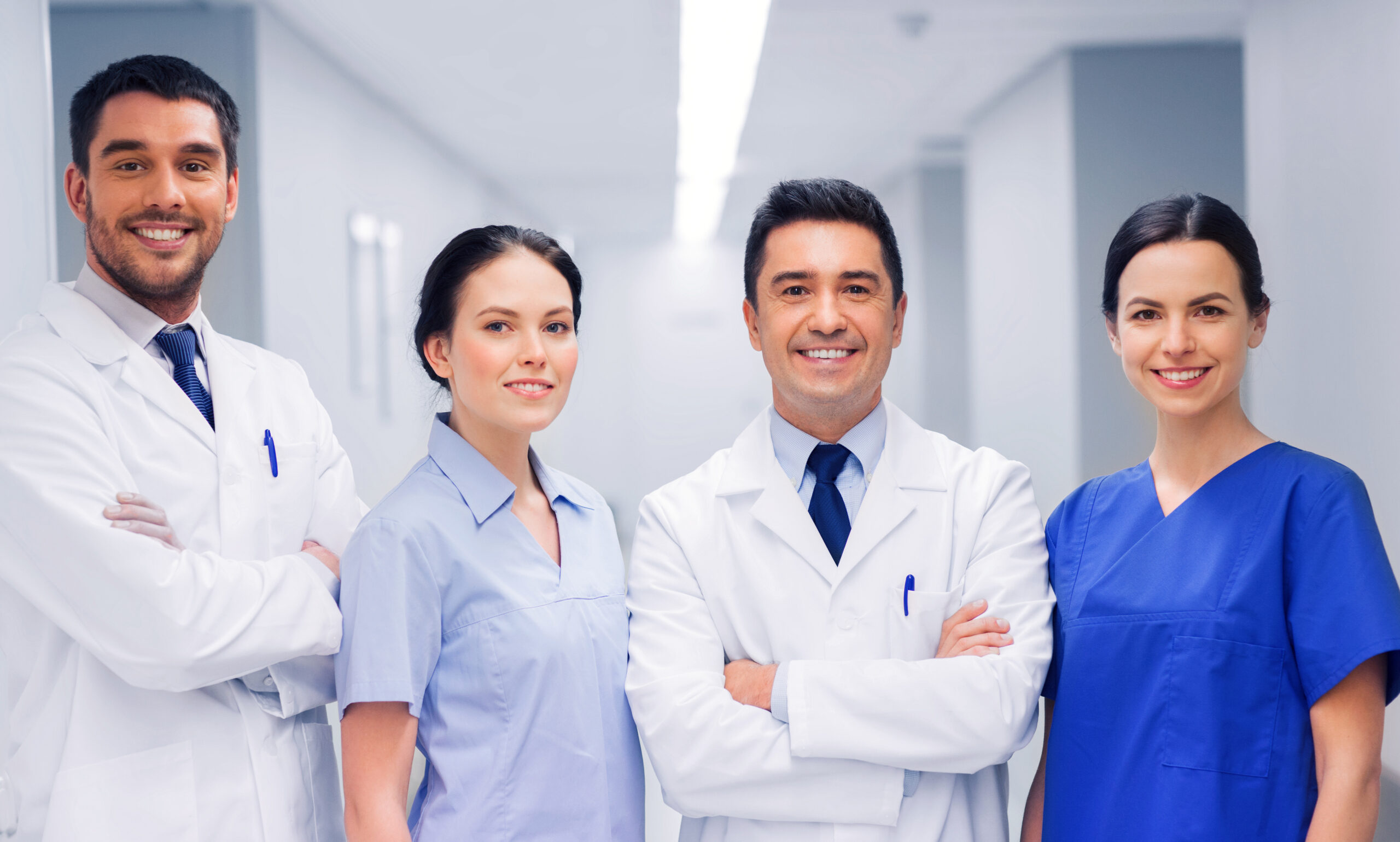 four medical professionals standing shoulder to shoulder smiling and crossing arms